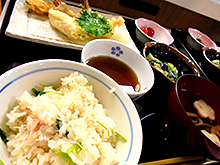 お膳の上にカニ飯、吸い物、天麩羅の盛り合わせ、酢の物、さくらんぼ